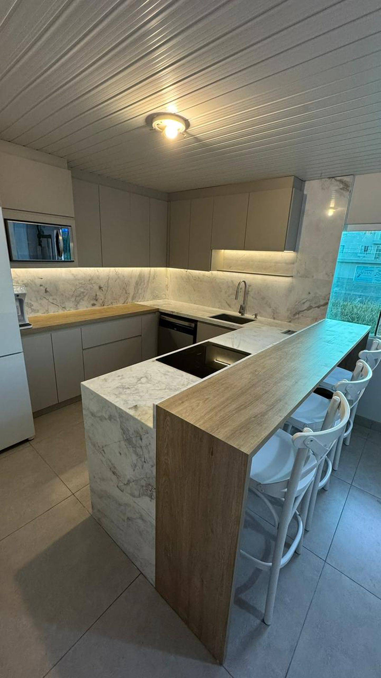 Cozinha em mármore branco Paraná com ilha central.